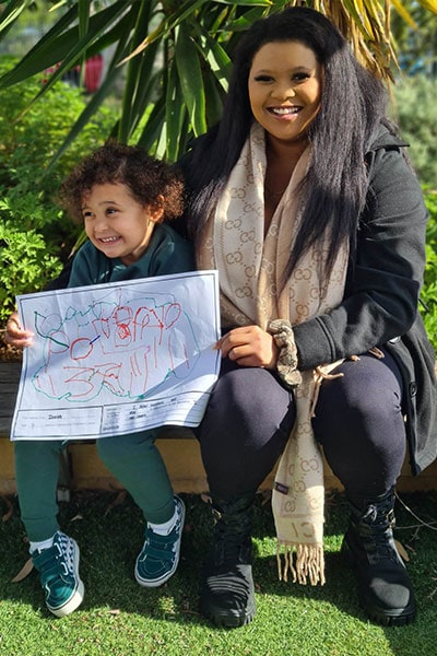 Isaiah, 4, sits with his mum Emily and shows her 'Important to Me' artwork